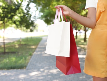 Photo of Young woman with shopping bags in sunny park, closeup