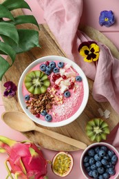 Flat lay composition with tasty smoothie bowl on pink wooden table