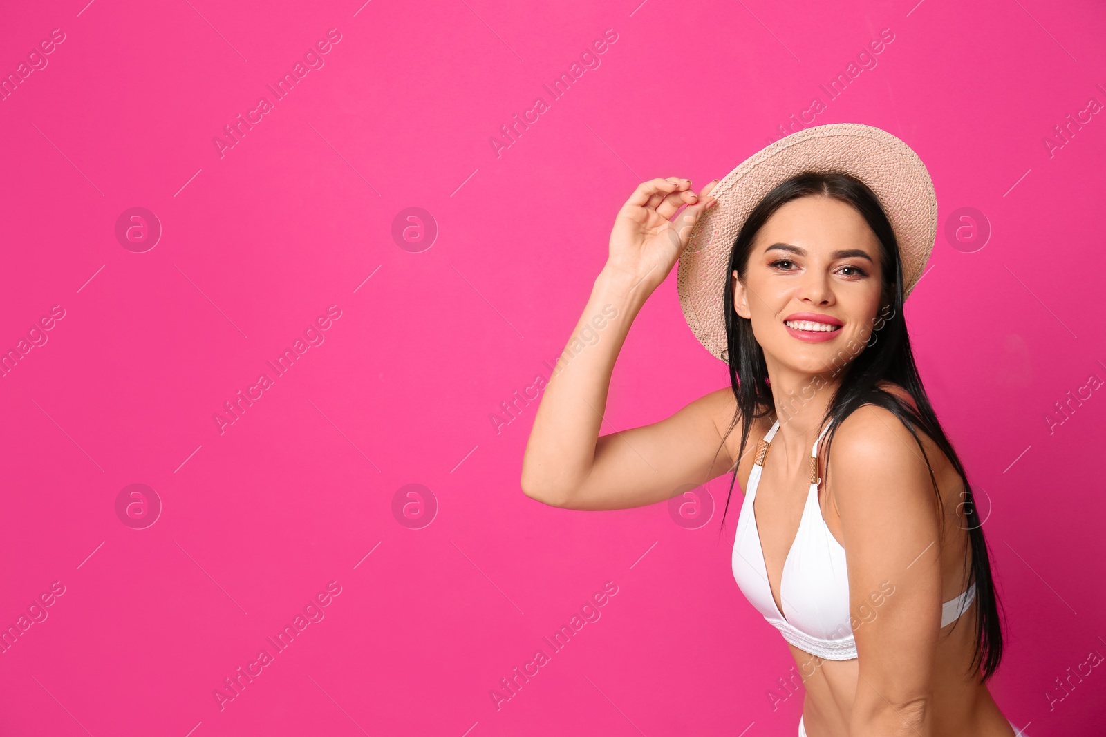 Photo of Beautiful young woman in white bikini with hat on pink background. Space for text