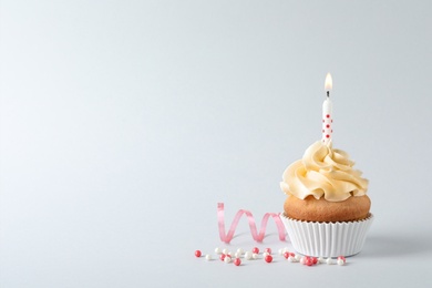 Delicious birthday cupcake with candle and space for text on gray background