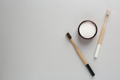 Photo of Jar of tooth powder and brushes on light grey background, flat lay. Space for text