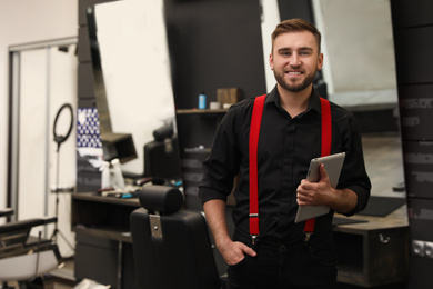 Photo of Young business owner with tablet in barber shop