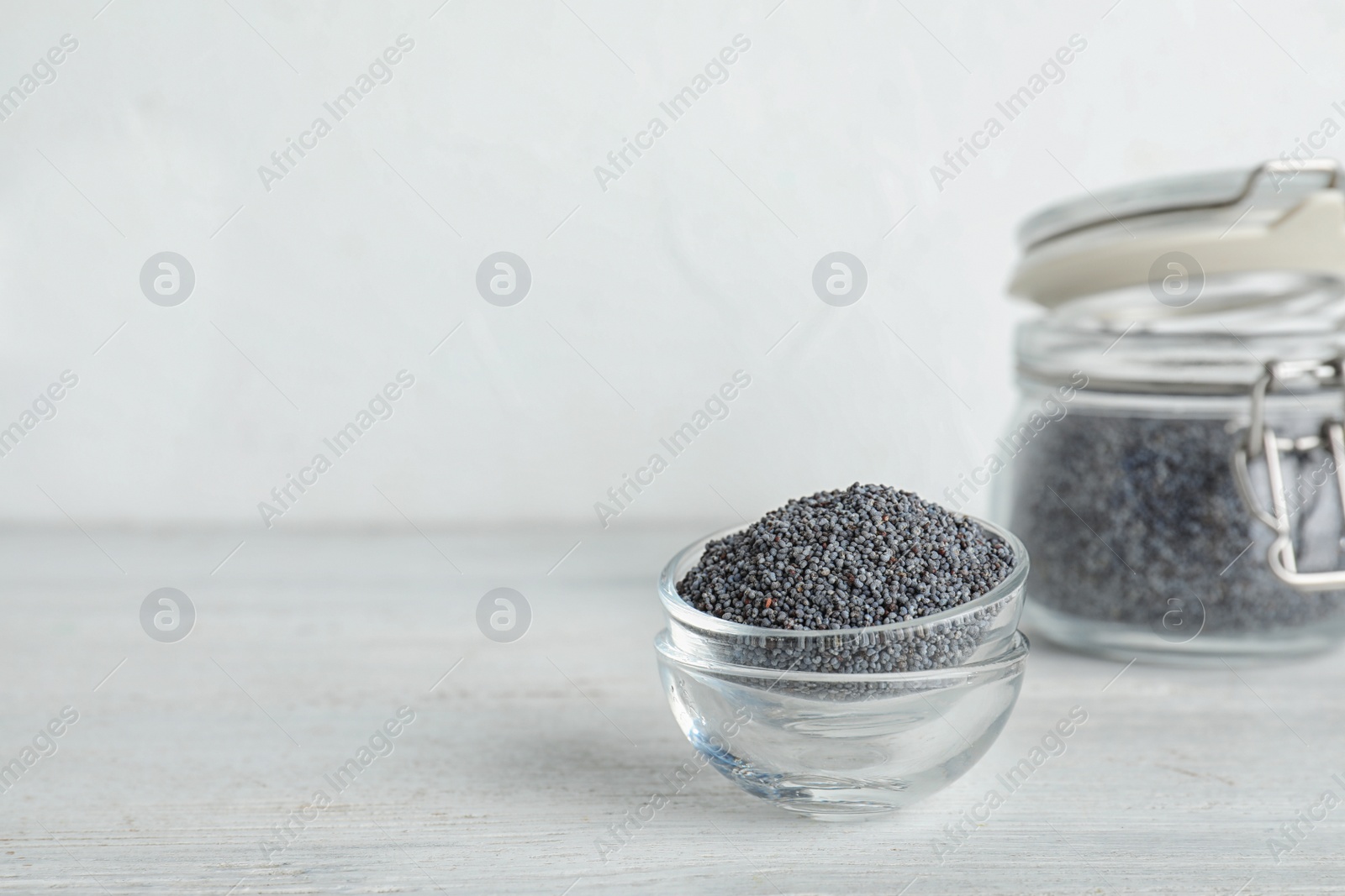 Photo of Poppy seeds in bowls on table. Space for text