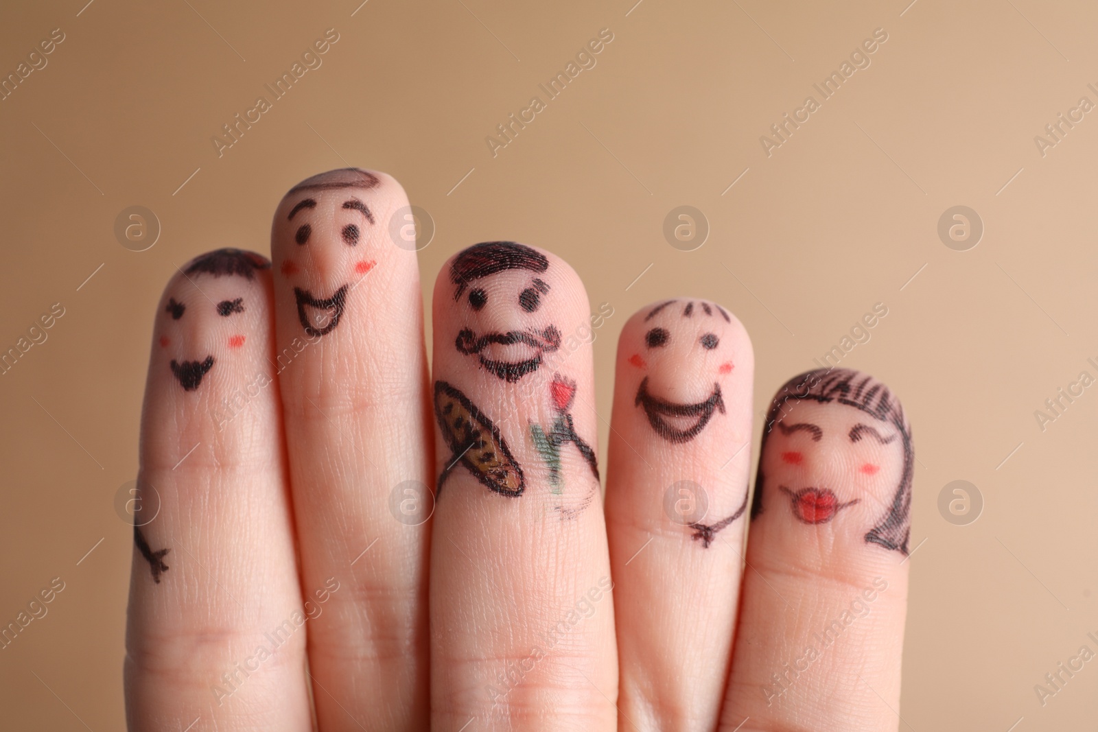 Photo of Five fingers with drawings of happy faces on brown background