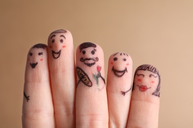 Photo of Five fingers with drawings of happy faces on brown background