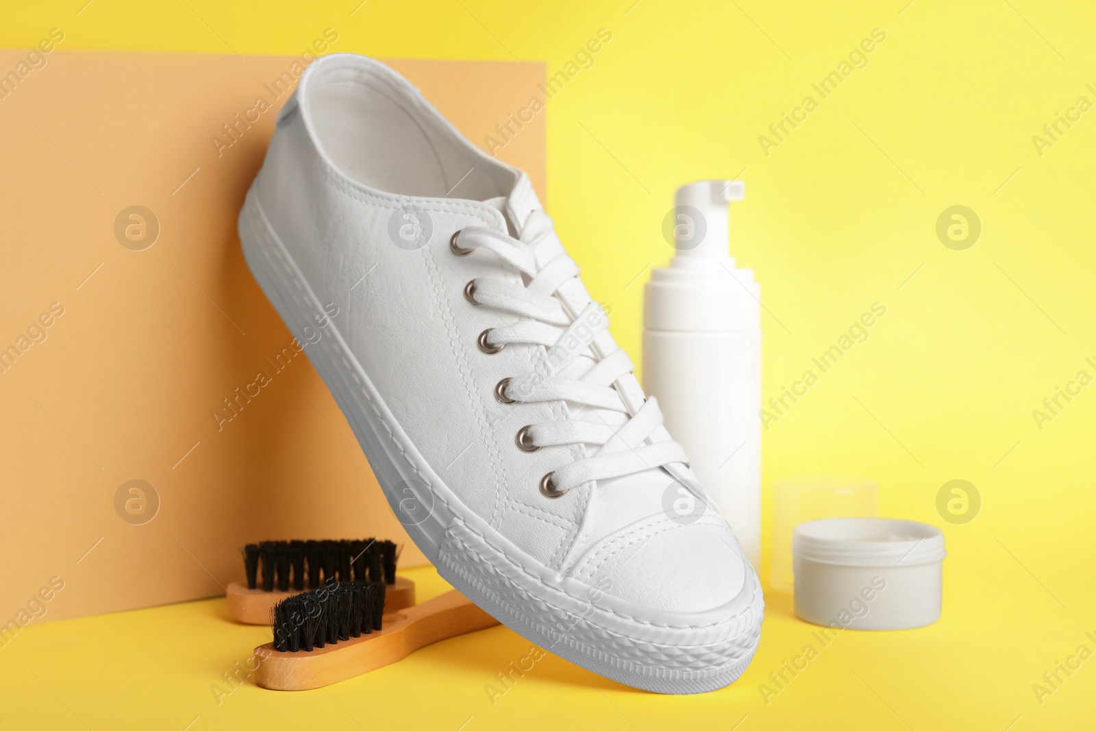 Photo of Composition with stylish footwear and shoe care accessories on yellow background