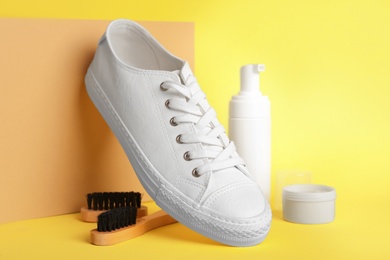 Composition with stylish footwear and shoe care accessories on yellow background