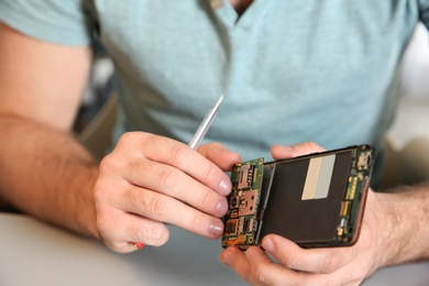 Photo of Technician repairing mobile phone at table, closeup