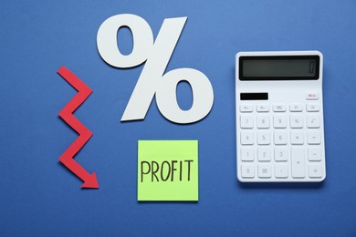 Sticky note with word Profit, calculator, percent symbol and up arrow on blue background, flat lay