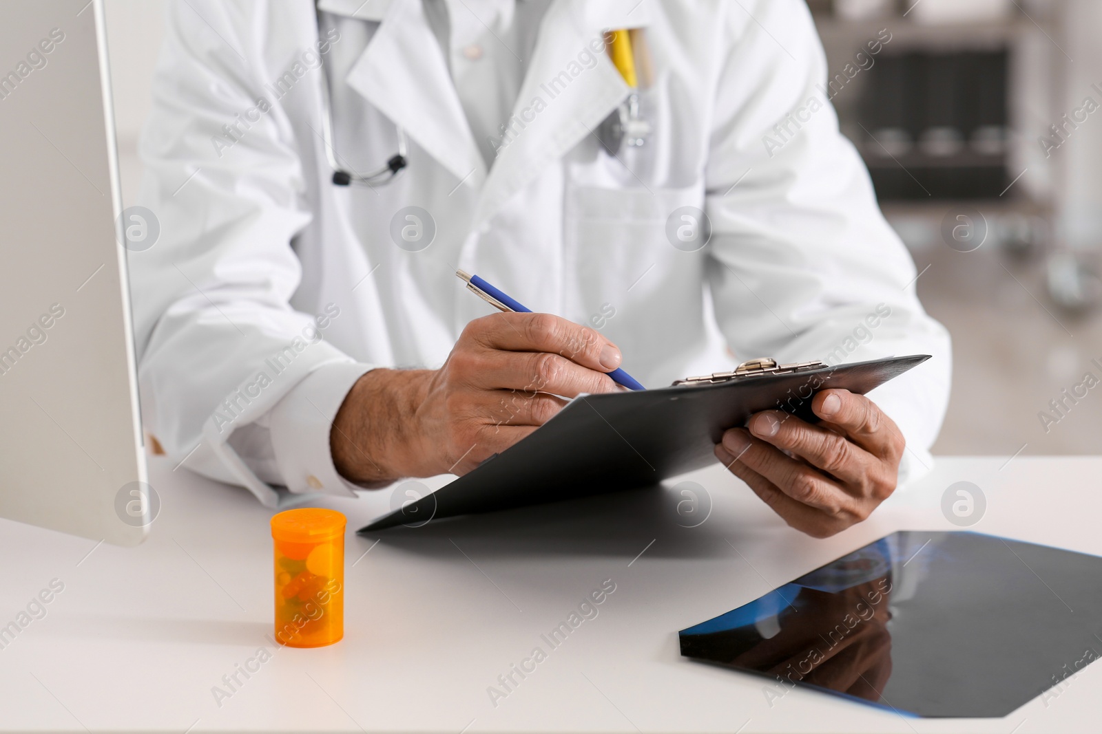 Photo of Doctor filling patient's medical card at table in clinic, closeup