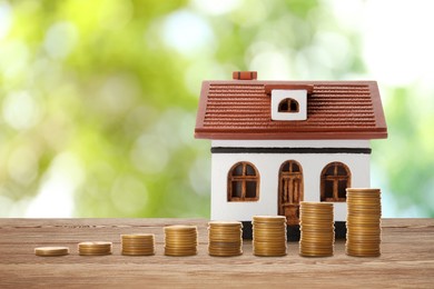 Image of Real estate investing. House model and coins on wooden table