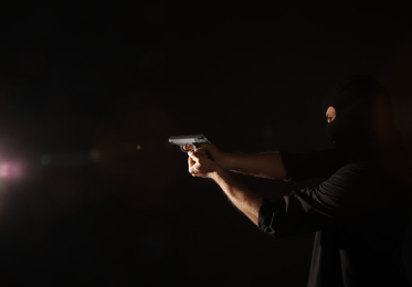 Photo of Professional killer with gun on black background