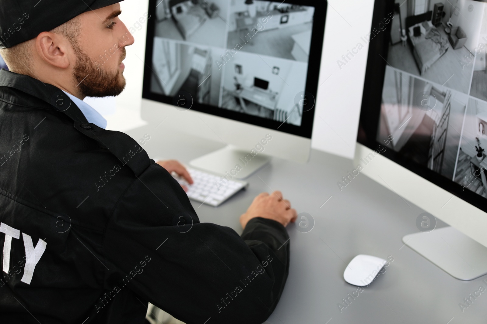 Photo of Male security guard monitoring home cameras indoors