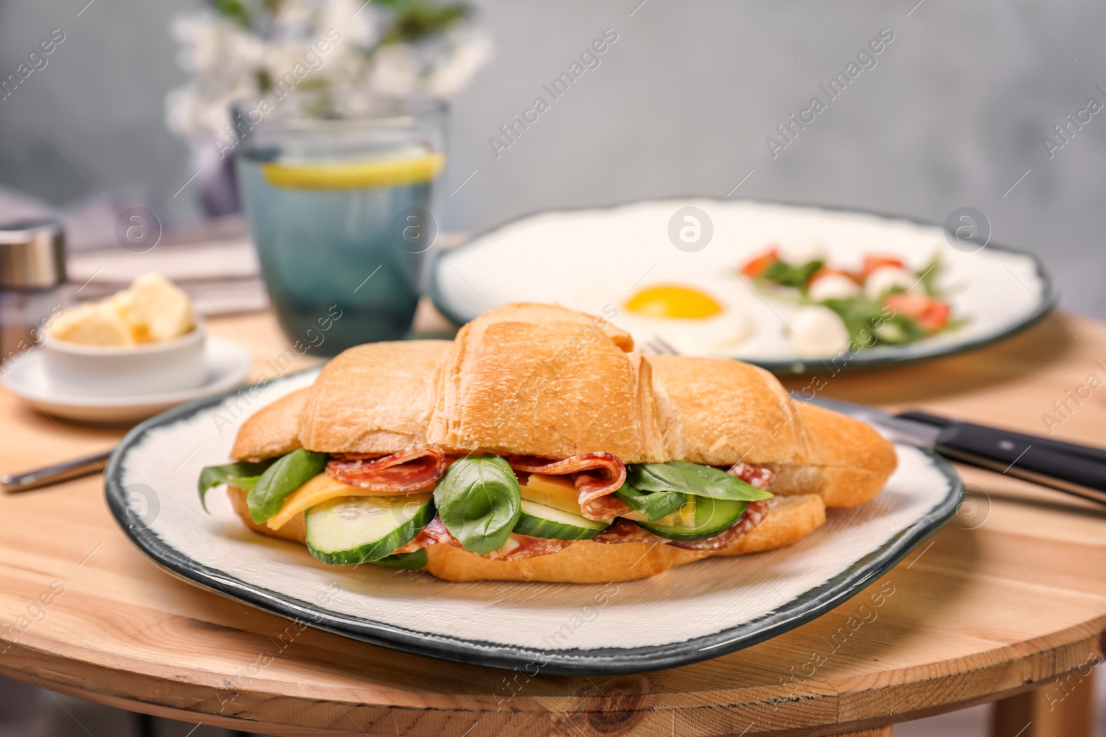 Photo of Plate with tasty croissant sandwich on table