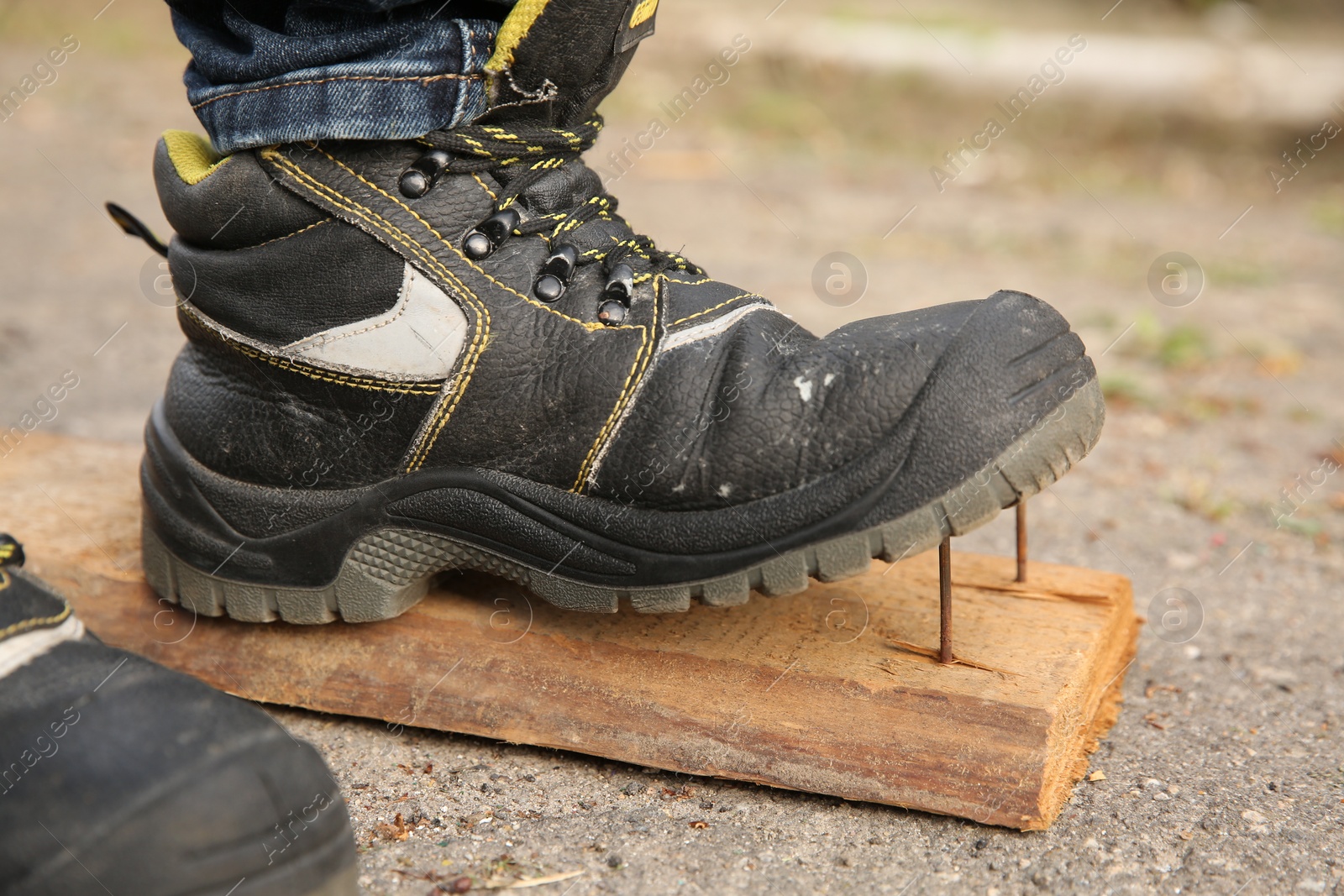 Photo of Careless worker stepping on nails in wooden plank outdoors, closeup