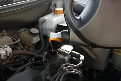Photo of Pouring motor oil into car engine, closeup