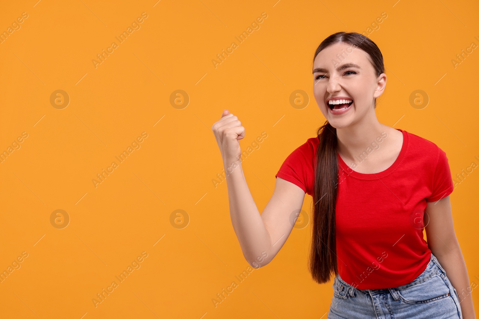 Photo of Emotional sports fan celebrating on orange background. Space for text