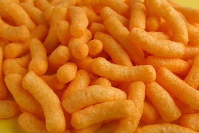 Tasty cheesy corn puffs as background, closeup