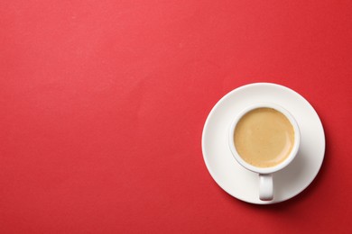 Photo of Aromatic coffee in cup on red background, top view. Space for text