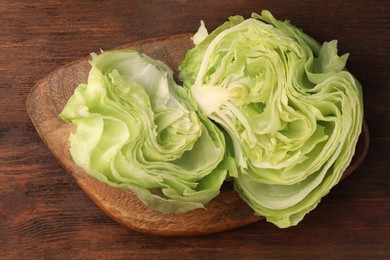 Board with fresh halves of iceberg lettuce head on wooden table, flat lay