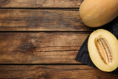 Photo of Delicious honey melon on wooden table, flat lay. Space for text