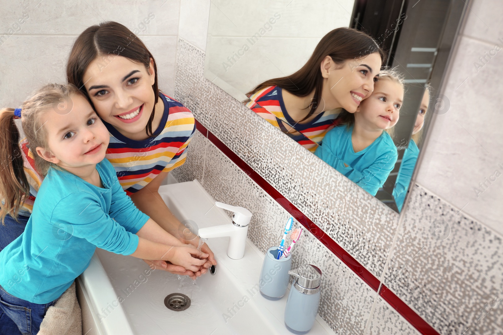 Photo of Happy mother and daughter washing hands in bathroom at home