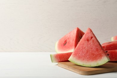 Photo of Delicious fresh watermelon slices on white wooden table. Space for text