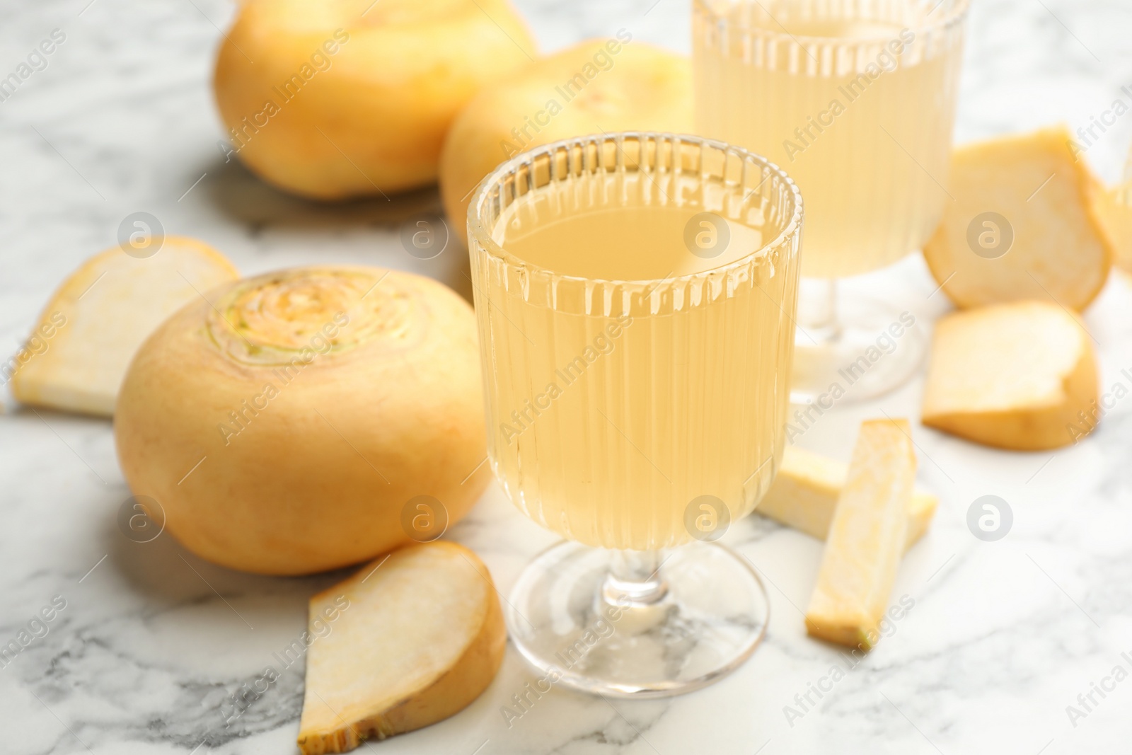 Photo of Glass of freshly made turnip juice on white marble table