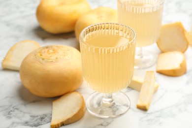 Glass of freshly made turnip juice on white marble table