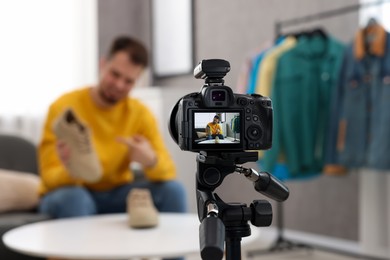Fashion blogger showing shoes while recording video at home, focus on camera