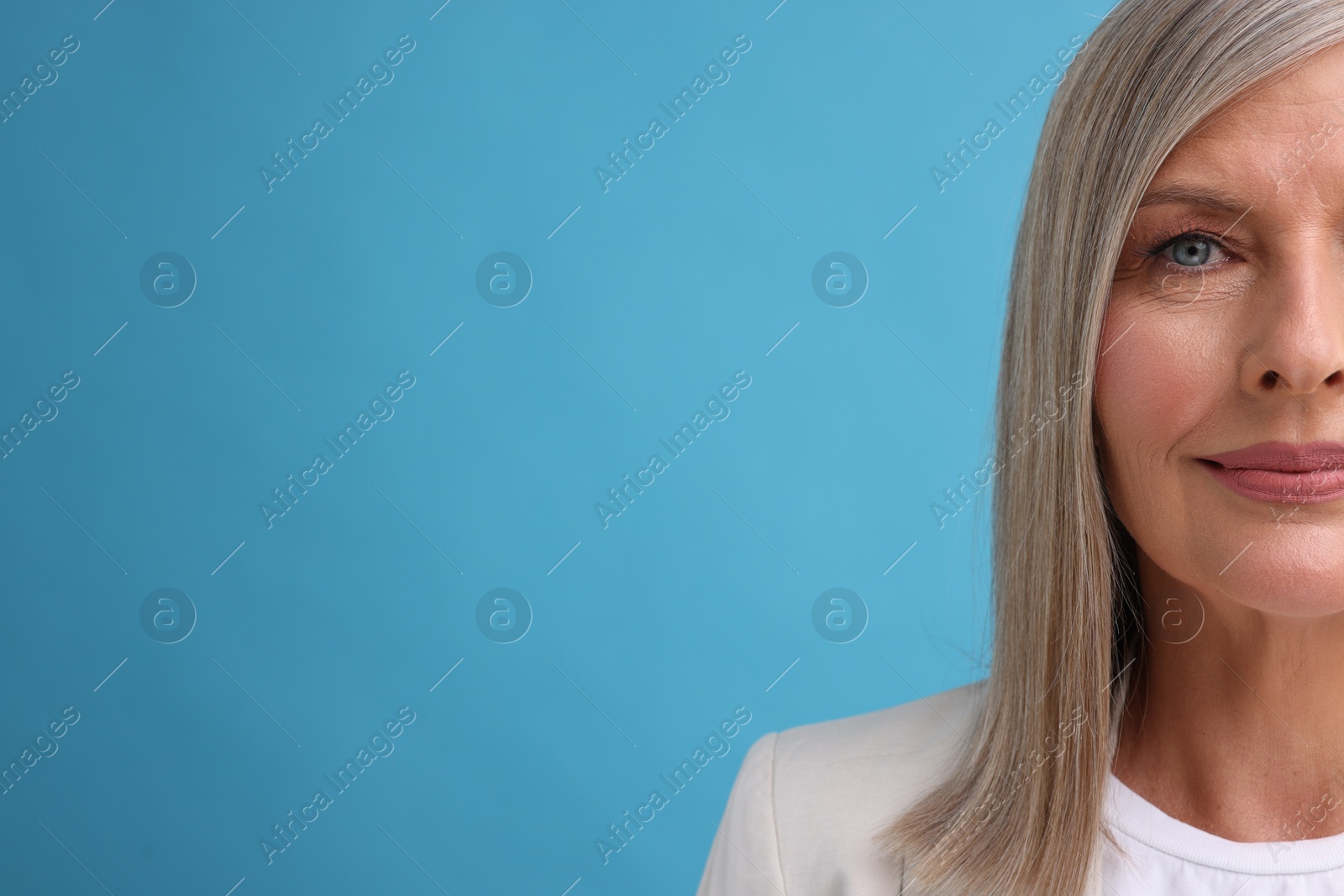 Photo of Portrait of beautiful middle aged woman on light blue background, closeup. Space for text