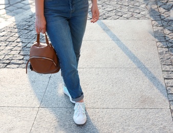 Woman in stylish sneakers walking outdoors, closeup