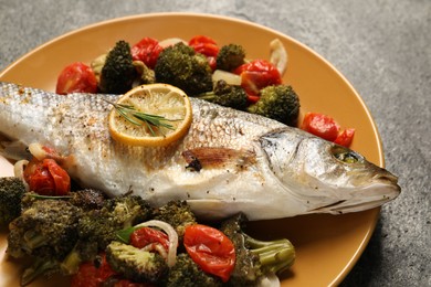 Photo of Delicious baked fish and vegetables on grey background, closeup