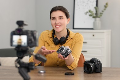 Smiling technology blogger recording video review about cameras at home