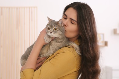 Photo of Young woman kissing her adorable cat at home