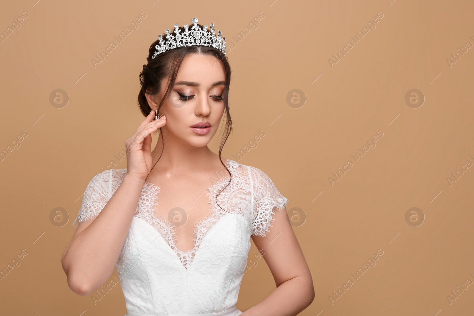 Photo of Beautiful young woman wearing luxurious tiara on beige background, space for text