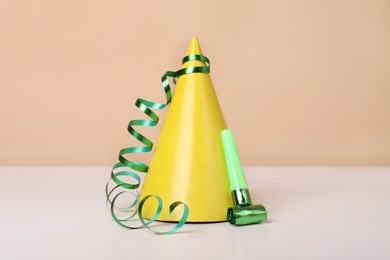 Colorful party hat, streamer and blower on white table. Birthday celebration