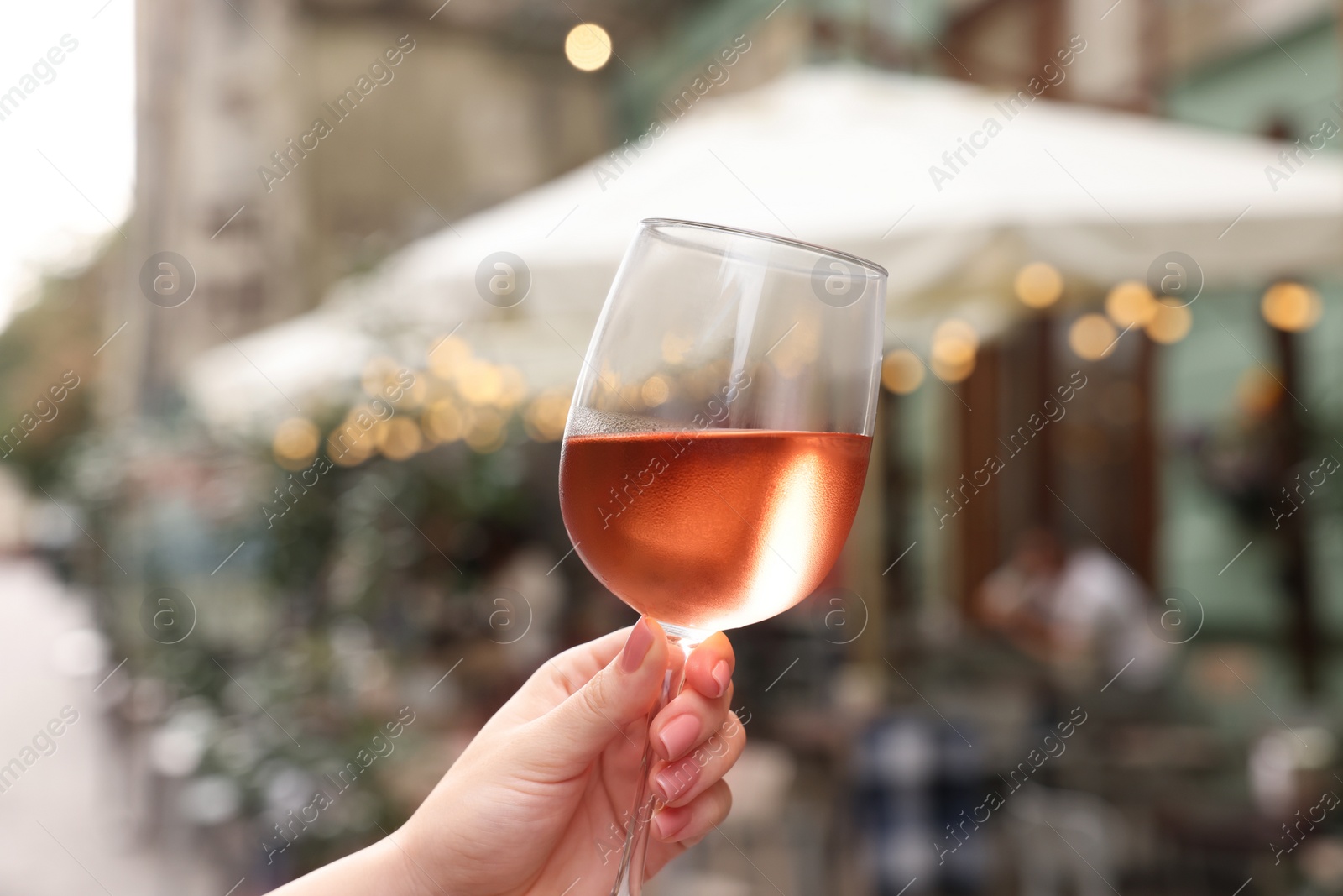 Photo of Woman holding glass of rose wine outdoors, closeup