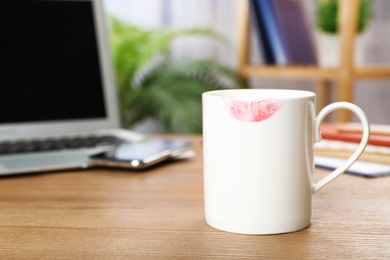 Ceramic cup with lipstick mark on table at workplace. Space for text