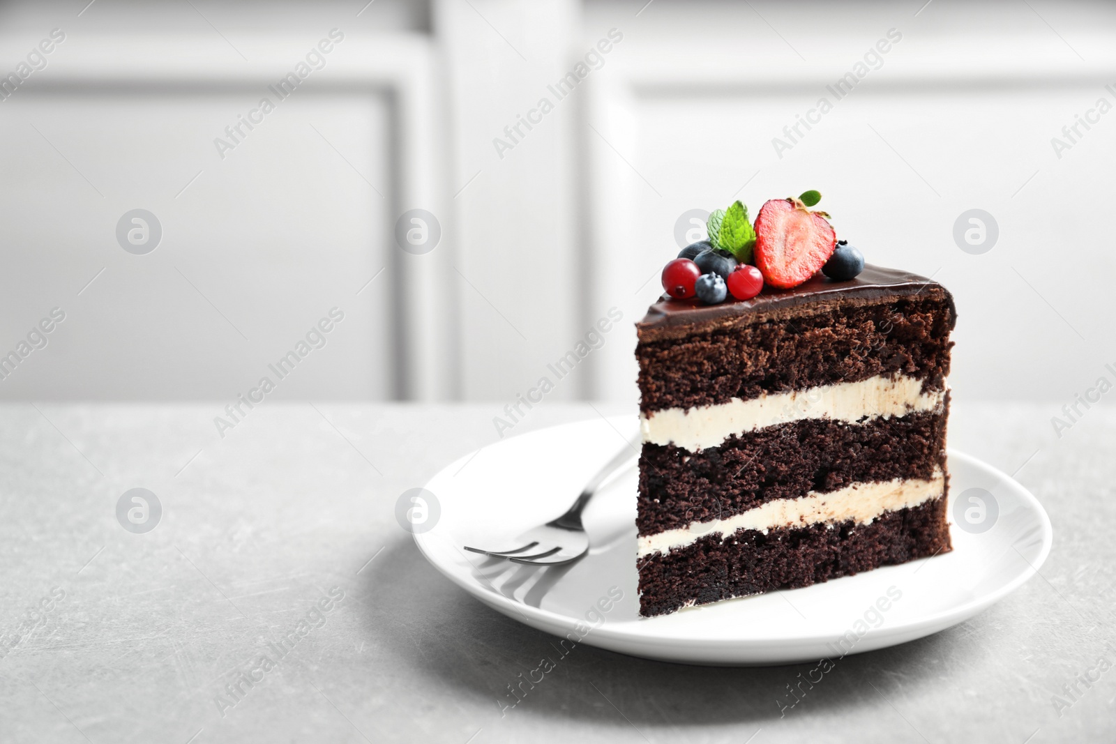 Photo of Plate with slice of chocolate sponge berry cake on grey table