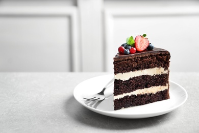 Plate with slice of chocolate sponge berry cake on grey table