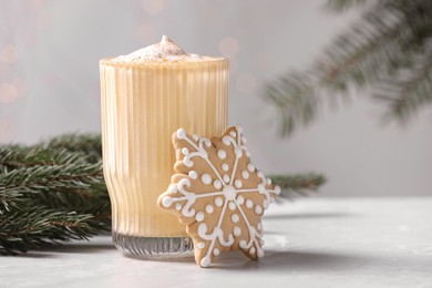 Tasty eggnog, cookie and fir branches on grey table
