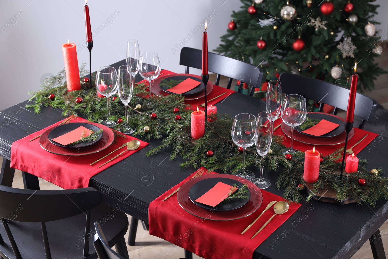 Photo of Elegant Christmas table setting with dishware and burning candles in festively decorated room