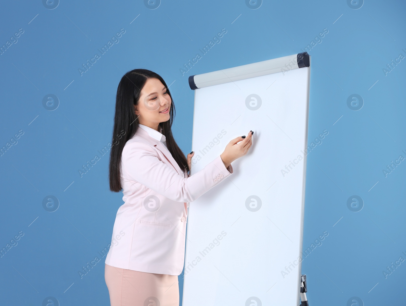 Photo of Business trainer giving presentation on flip chart board against color background