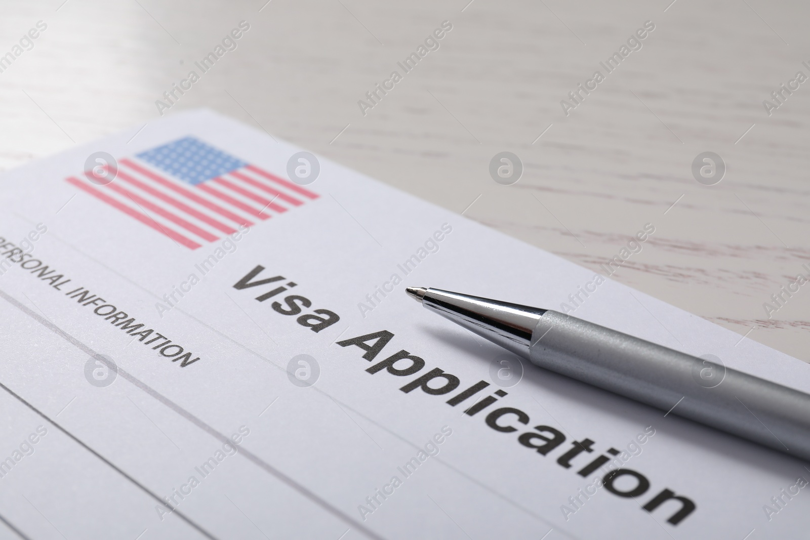 Photo of Immigration to USA. Visa application form and pen on white wooden table, closeup