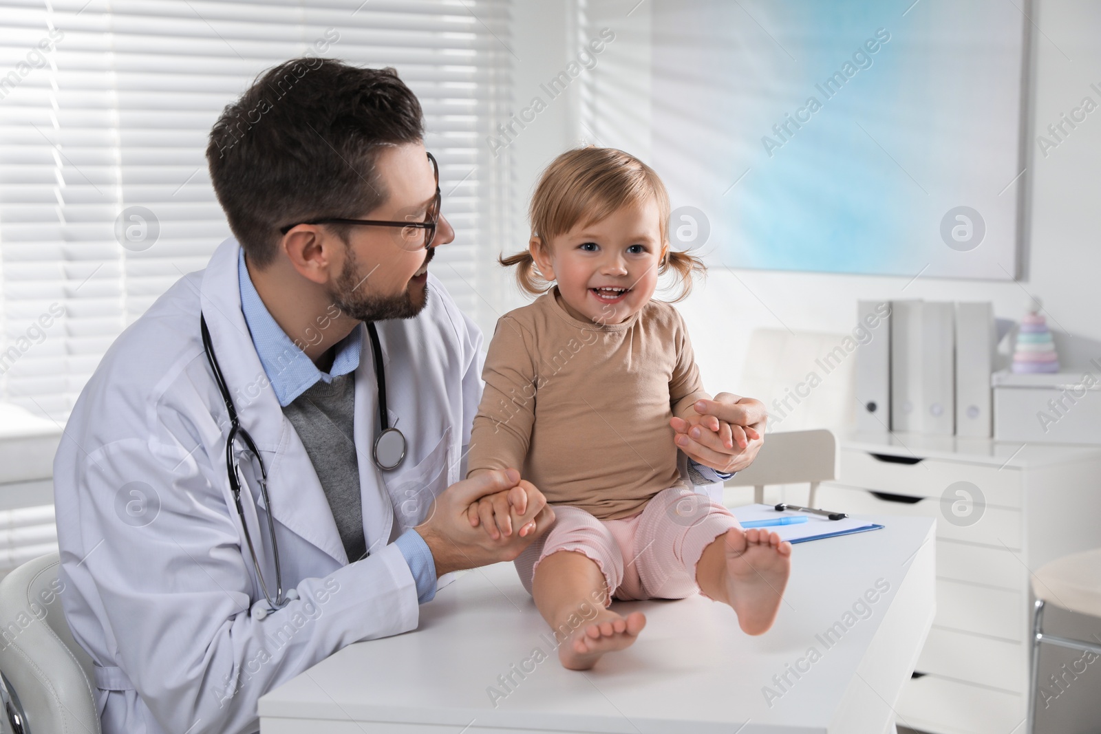 Photo of Pediatrician examining cute little baby in clinic