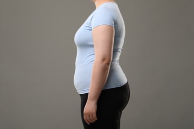 Overweight woman on grey background, closeup view