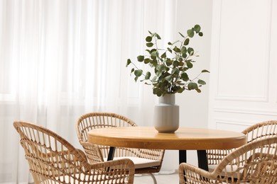 Photo of Dining room interior with comfortable furniture and eucalyptus branches