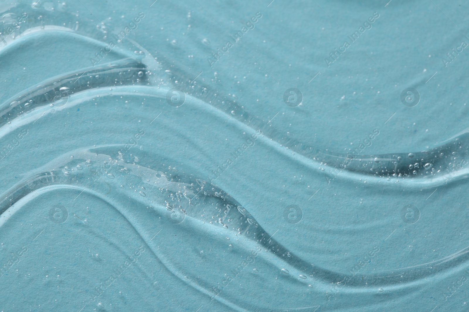 Photo of Clear cosmetic serum on light blue background, macro view