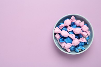 Candies in colorful wrapper on pink background, top view. Space for text